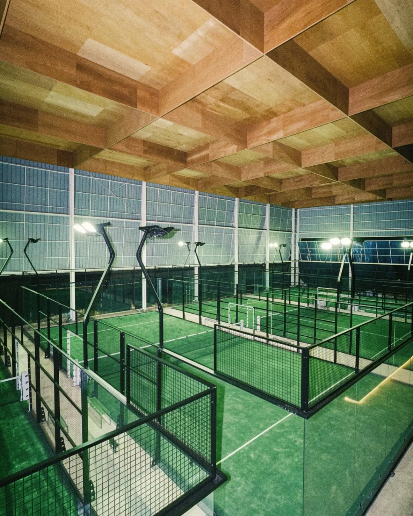 Four green padel courts under the timber-slat roof at Moss Padel Park