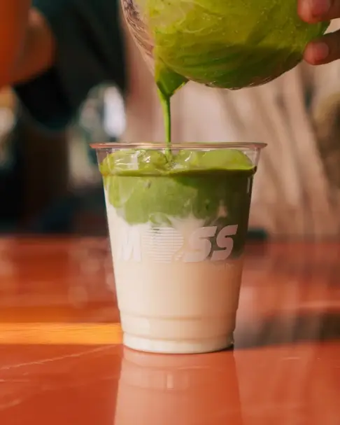 Matcha latte being poured over milk